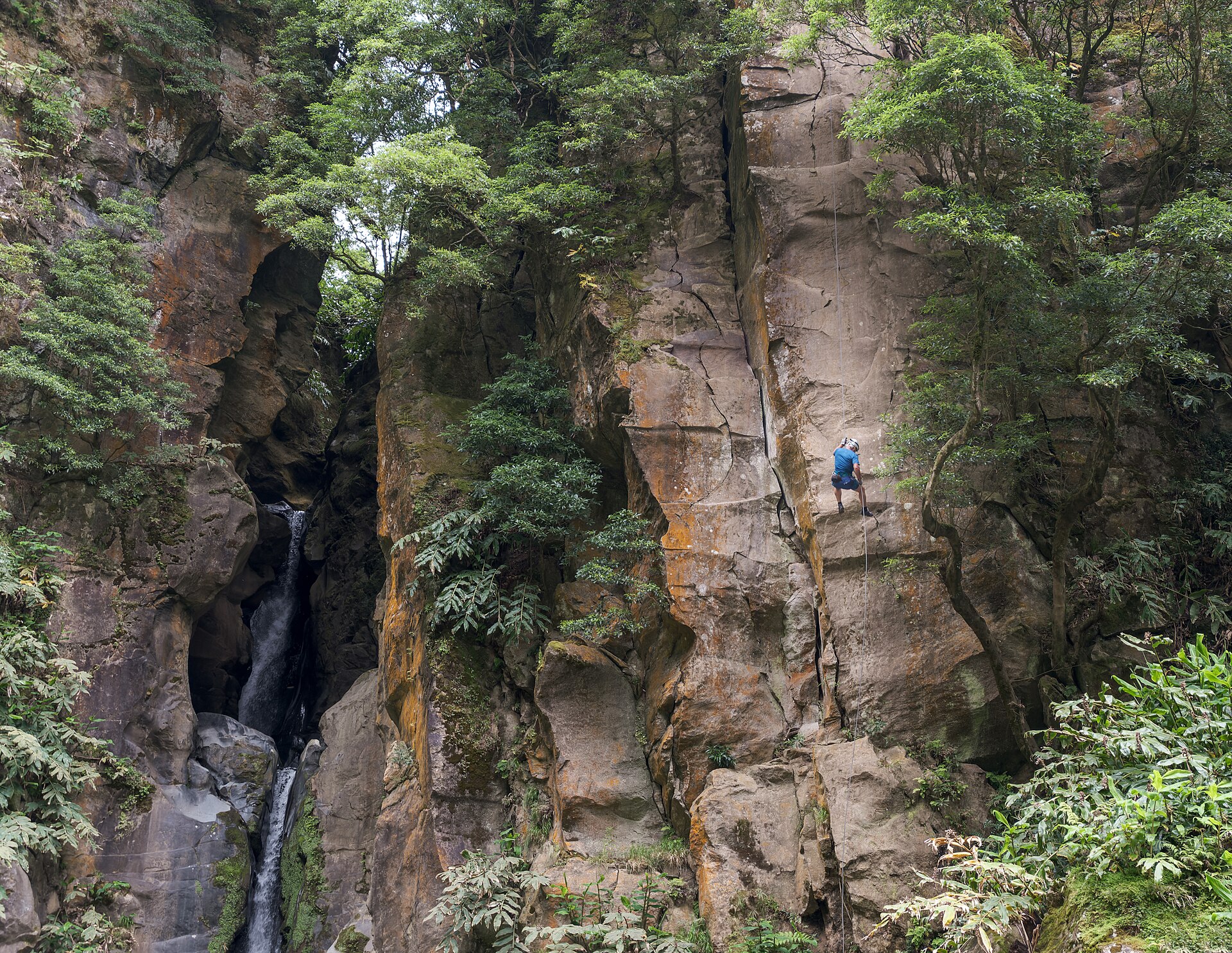 Pessoa a fazer rappel de canyoning na cascata do Salto do Cabrito em São Miguel nos Açores