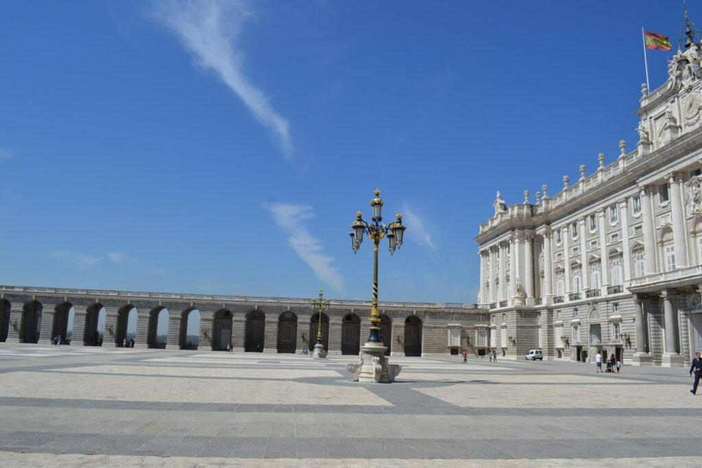 Fachada del Palacio Real de Madrid y Plaza de la Armería bajo un cielo azul