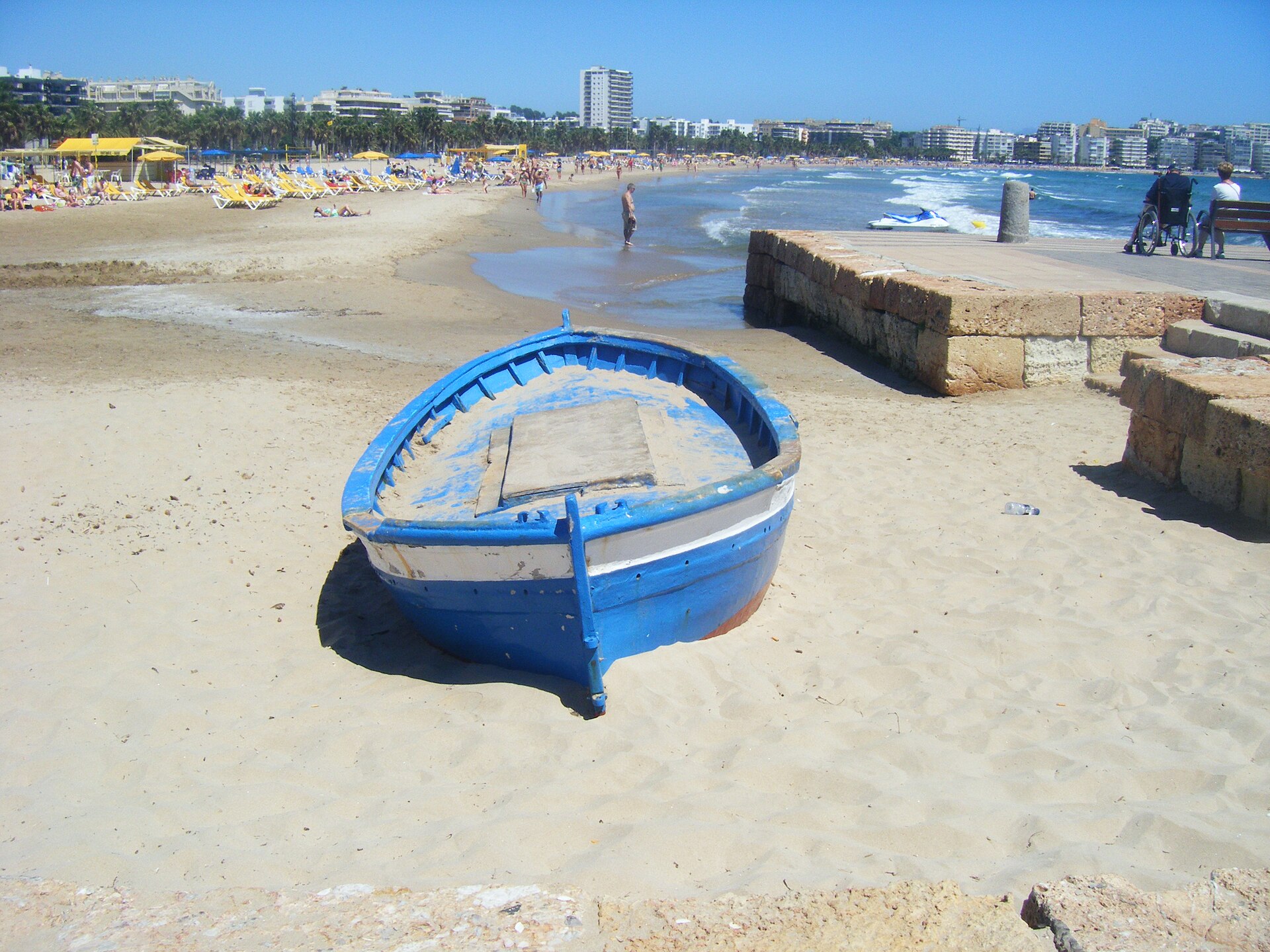 Blue boat on the sand with Salou's seafront behind it